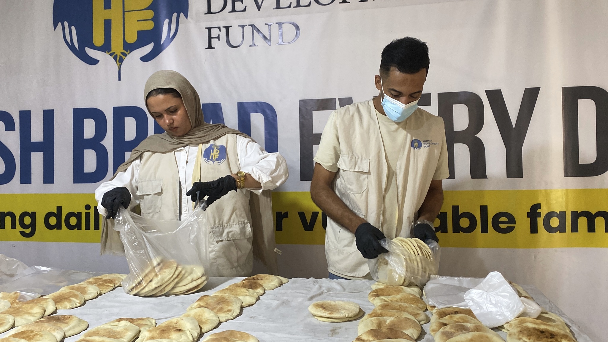 Two HDF team members pack freshly baked bread into bags for local distribution